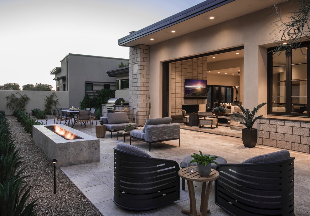 This is an example of a large contemporary backyard patio in Phoenix with a fire feature, natural stone pavers and no cover.