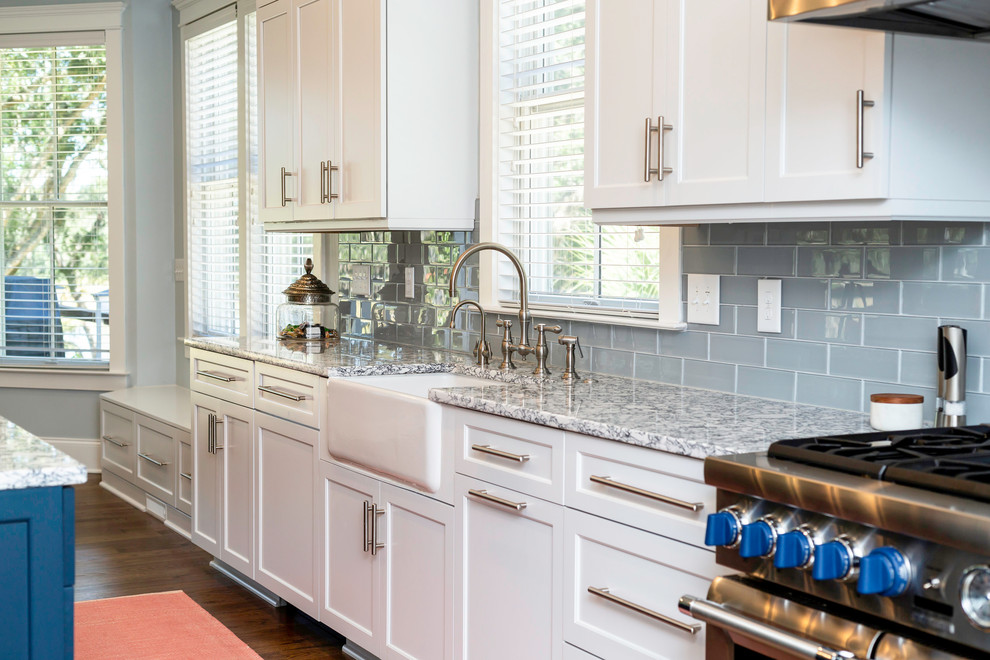 Photo of a transitional single-wall eat-in kitchen in Charleston with a farmhouse sink, shaker cabinets, white cabinets, quartzite benchtops, blue splashback, stainless steel appliances, medium hardwood floors, with island, brown floor and grey benchtop.