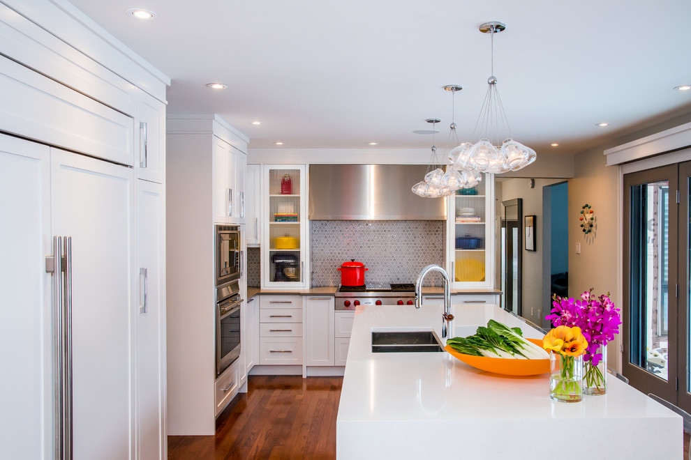Example of a large transitional l-shaped medium tone wood floor eat-in kitchen design in Calgary with an undermount sink, shaker cabinets, white cabinets, quartz countertops, multicolored backsplash, mosaic tile backsplash, paneled appliances and an island