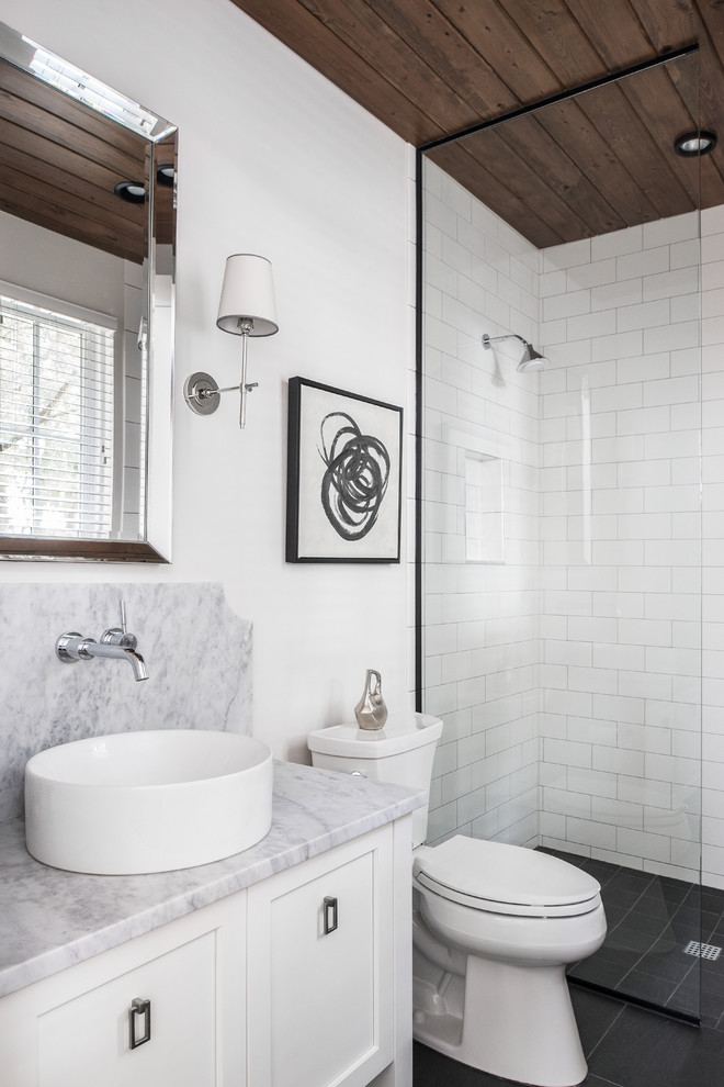 This is an example of a transitional 3/4 bathroom in Orlando with shaker cabinets, white cabinets, a two-piece toilet, white tile, subway tile, white walls, a vessel sink, black floor, an open shower and an alcove shower.