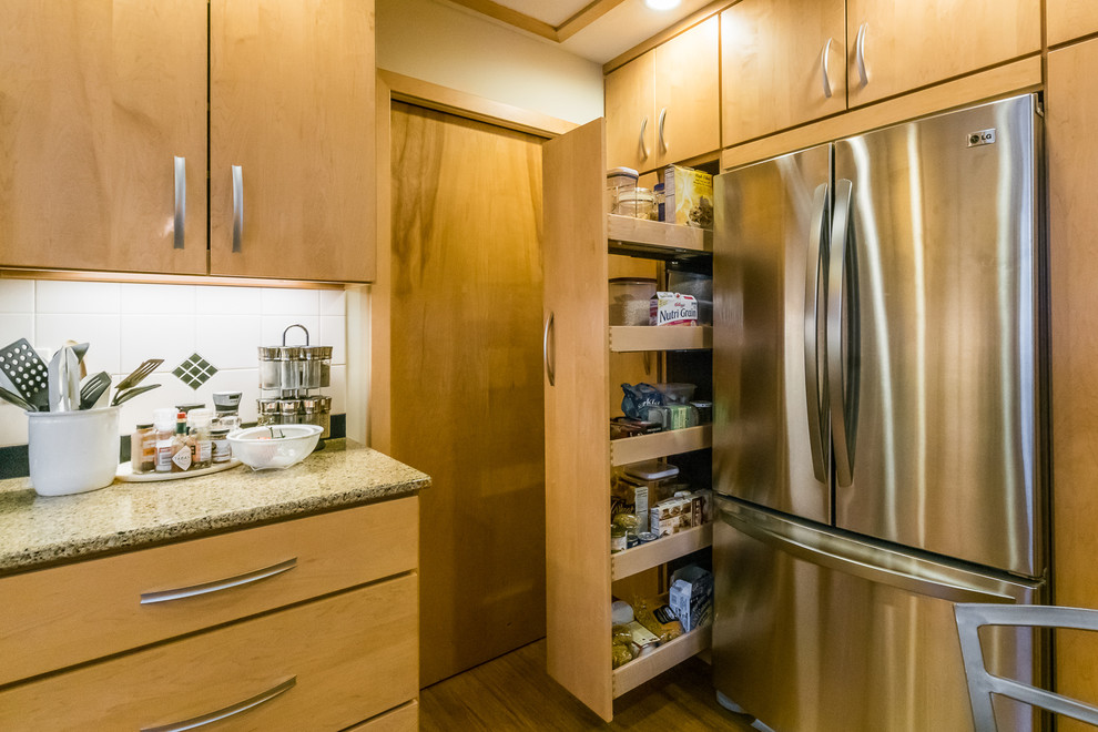 Photo of a mid-sized midcentury u-shaped separate kitchen in Chicago with an undermount sink, flat-panel cabinets, light wood cabinets, granite benchtops, white splashback, ceramic splashback, stainless steel appliances, bamboo floors and with island.