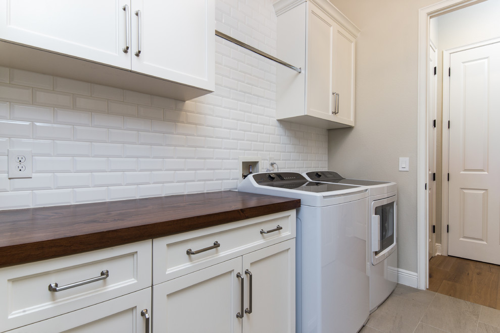 Traditional laundry room in Orlando with beaded inset cabinets, white cabinets, wood benchtops, beige walls, ceramic floors, a side-by-side washer and dryer and beige floor.