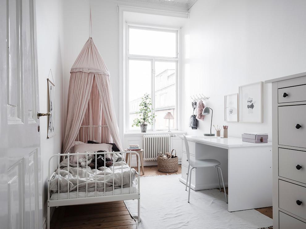 Photo of a mid-sized scandinavian kids' bedroom for kids 4-10 years old and girls in Gothenburg with white walls, medium hardwood floors and brown floor.