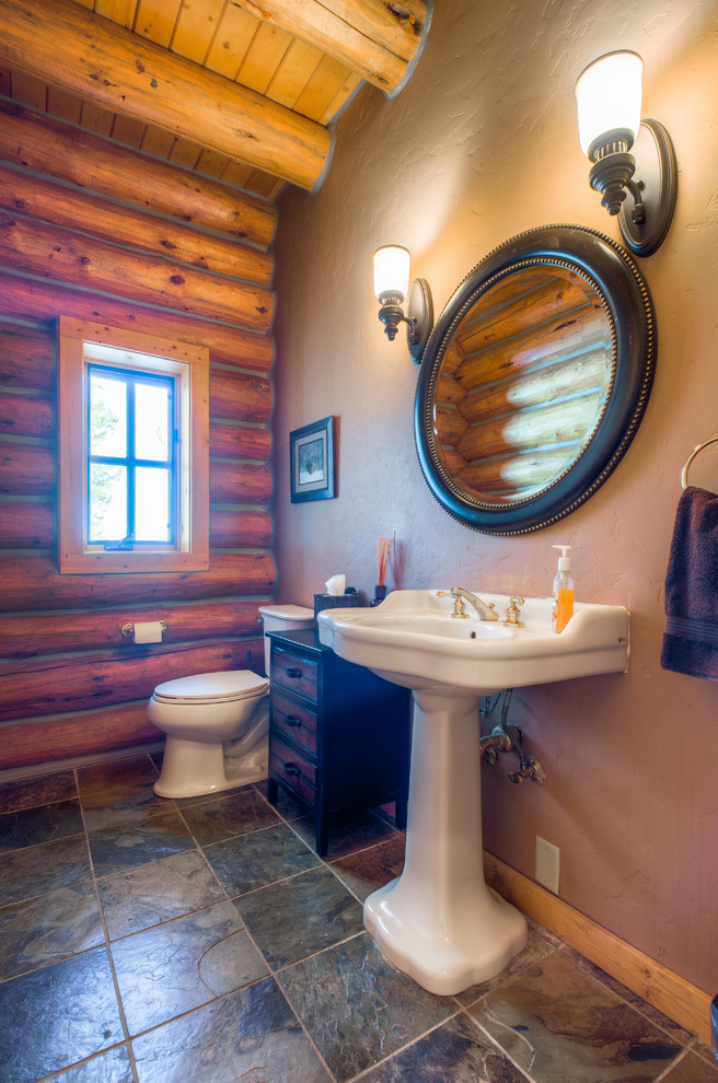 This is an example of a small country powder room in Denver with a one-piece toilet, white walls, ceramic floors and a pedestal sink.
