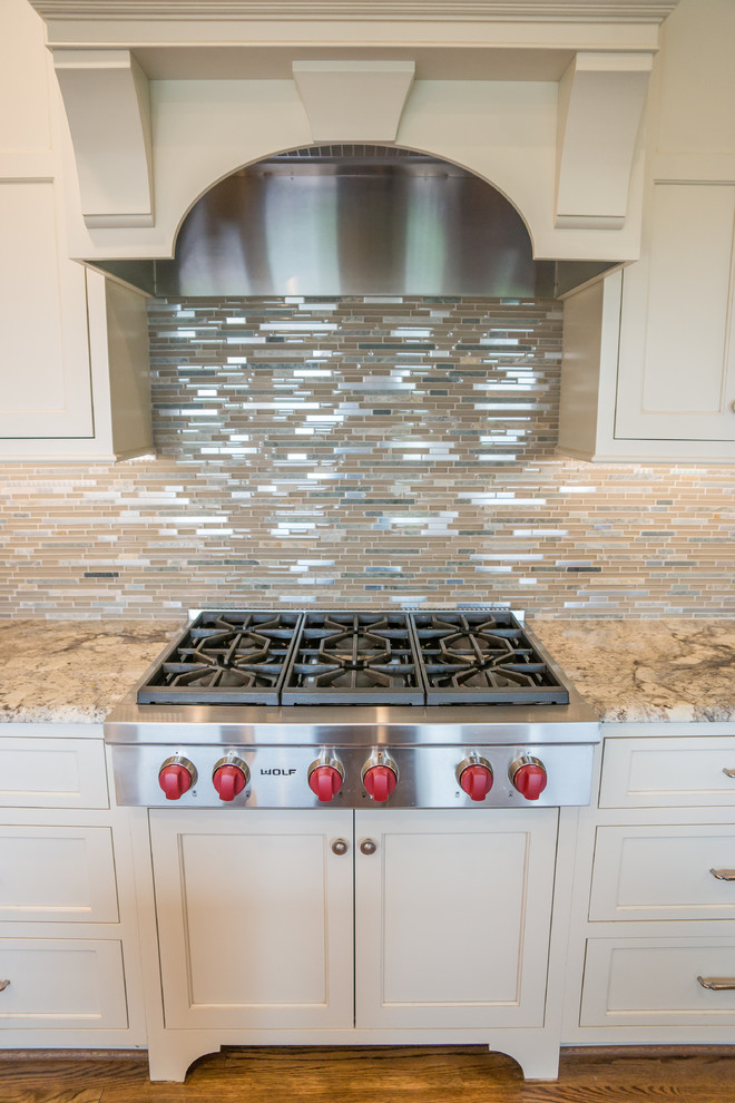 Inspiration for a huge transitional l-shaped medium tone wood floor eat-in kitchen remodel in Birmingham with an undermount sink, recessed-panel cabinets, white cabinets, granite countertops, multicolored backsplash, glass tile backsplash, stainless steel appliances and an island