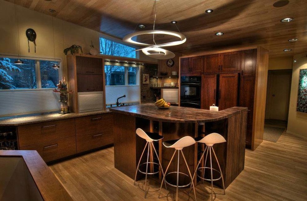 Eat-in kitchen - small rustic l-shaped light wood floor eat-in kitchen idea with a double-bowl sink, dark wood cabinets, granite countertops, paneled appliances and an island