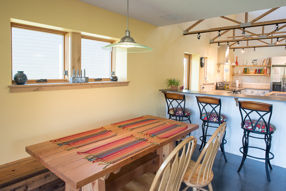 Example of a small mountain style concrete floor and gray floor kitchen/dining room combo design with yellow walls and no fireplace