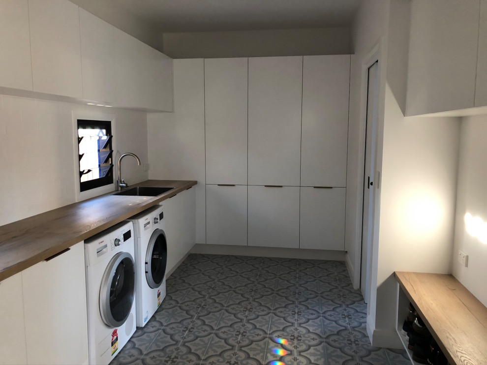Design ideas for a contemporary l-shaped dedicated laundry room in Sydney with wood benchtops, ceramic floors and a side-by-side washer and dryer.