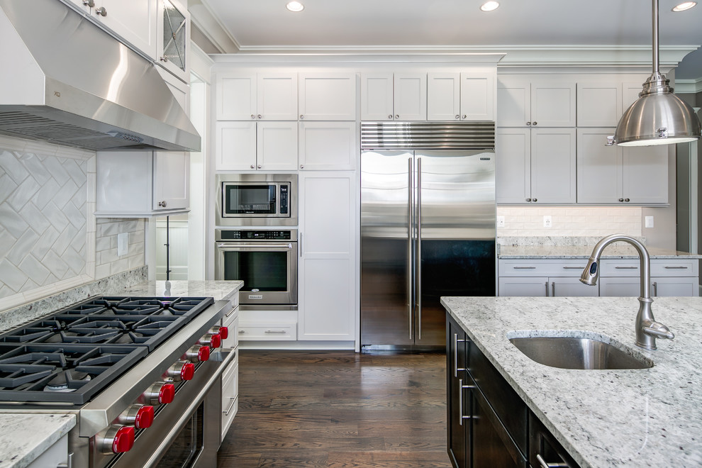 Example of a large transitional u-shaped dark wood floor enclosed kitchen design in DC Metro with a drop-in sink, recessed-panel cabinets, white cabinets, granite countertops, white backsplash, subway tile backsplash, stainless steel appliances and an island