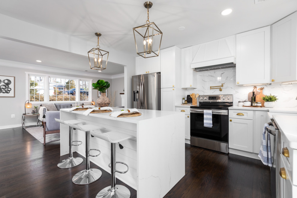 This is an example of a mid-sized transitional eat-in kitchen in DC Metro with shaker cabinets, white cabinets, marble benchtops, white splashback, marble splashback, stainless steel appliances, dark hardwood floors, with island, brown floor and white benchtop.