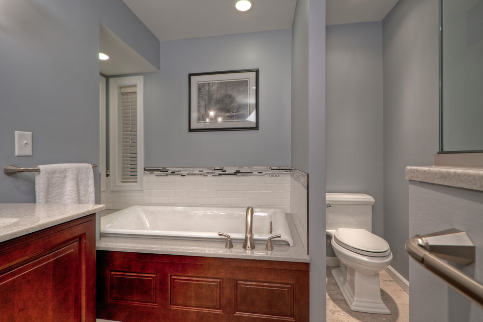 Large contemporary master bathroom in St Louis with an integrated sink, recessed-panel cabinets, medium wood cabinets, onyx benchtops, an alcove tub, a corner shower, a one-piece toilet, multi-coloured tile, glass tile, grey walls and ceramic floors.