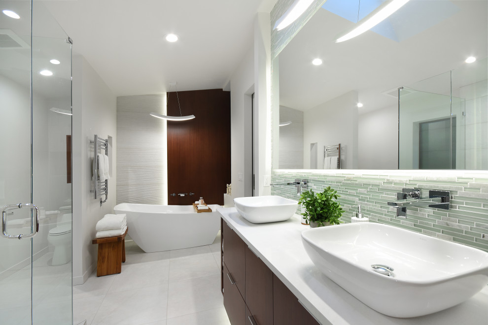 This is an example of a large contemporary master bathroom in Seattle with flat-panel cabinets, dark wood cabinets, a freestanding tub, a double shower, a one-piece toilet, white tile, porcelain tile, white walls, porcelain floors, a vessel sink, engineered quartz benchtops, white floor, a hinged shower door, white benchtops, a niche, a double vanity, a built-in vanity and wood walls.