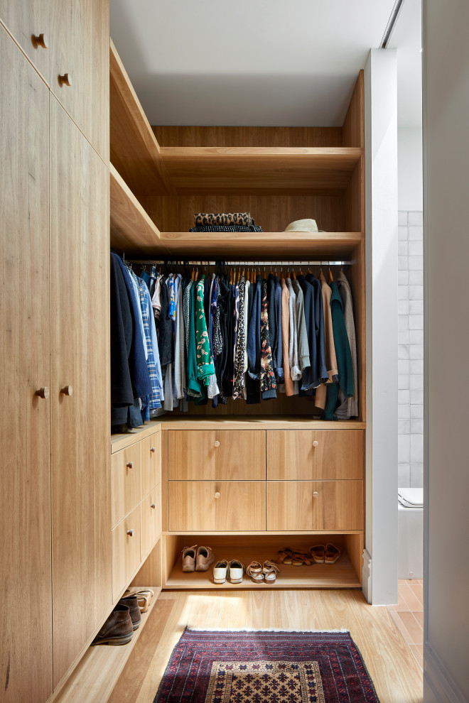 Esempio di una piccola cabina armadio unisex minimal con ante lisce, ante in legno chiaro, parquet chiaro e pavimento marrone