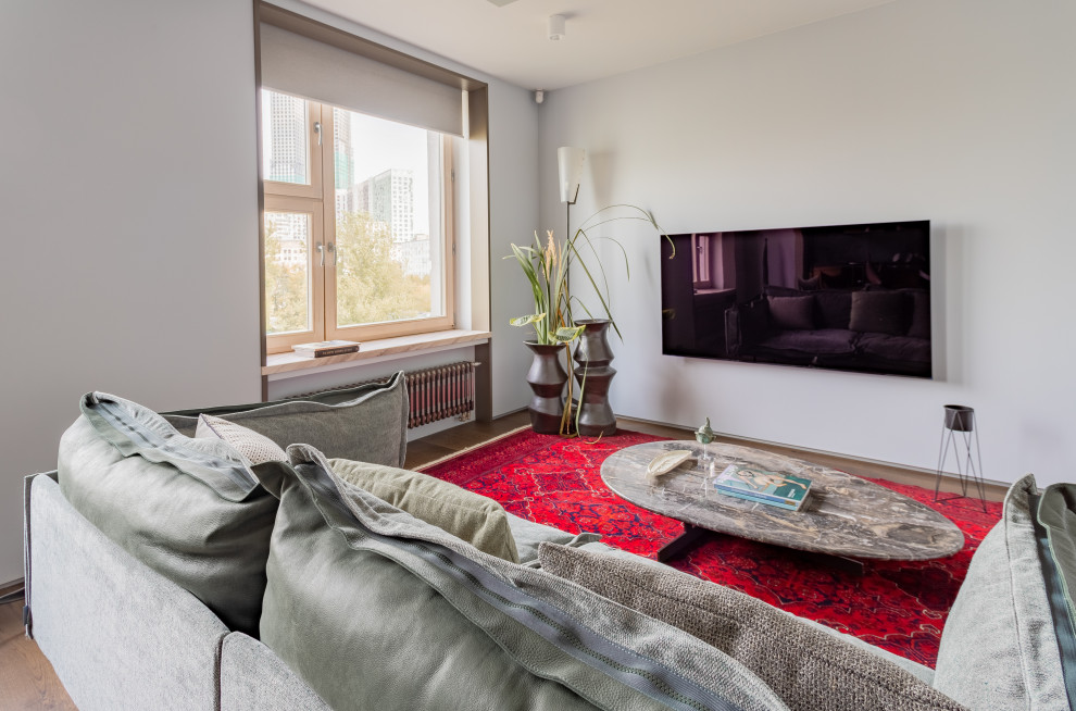 На фото: открытая гостиная комната среднего размера в современном стиле с серыми стенами, паркетным полом среднего тона, телевизором на стене, коричневым полом и ковром на полу