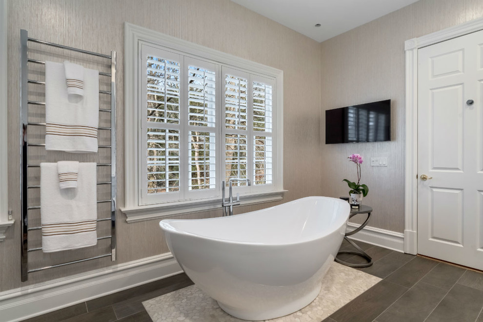This is an example of a mid-sized transitional 3/4 bathroom in New York with flat-panel cabinets, white cabinets, a freestanding tub, a one-piece toilet, beige walls, porcelain floors, an undermount sink and solid surface benchtops.