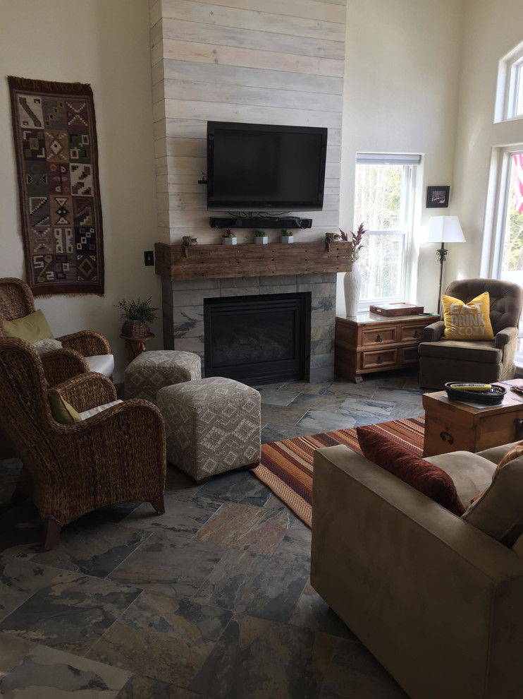 Photo of a mid-sized country formal enclosed living room in Denver with beige walls, slate floors, a standard fireplace, a wood fireplace surround, a wall-mounted tv and multi-coloured floor.