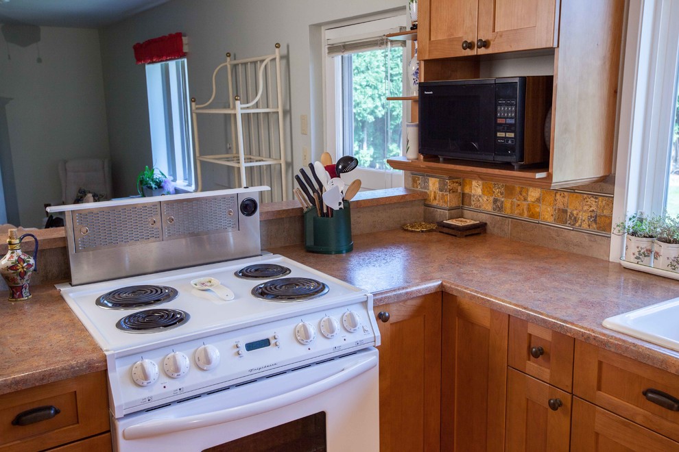 Mid-sized transitional l-shaped cork floor eat-in kitchen photo in Seattle with a drop-in sink, shaker cabinets, medium tone wood cabinets, wood countertops, brown backsplash, ceramic backsplash, white appliances and an island