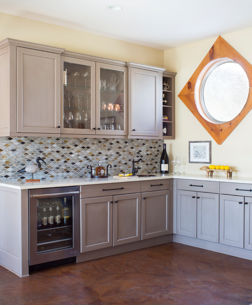 Photo of a mid-sized transitional l-shaped wet bar in Denver with an undermount sink, shaker cabinets, grey cabinets, quartz benchtops, multi-coloured splashback, mosaic tile splashback, concrete floors, white benchtop and brown floor.