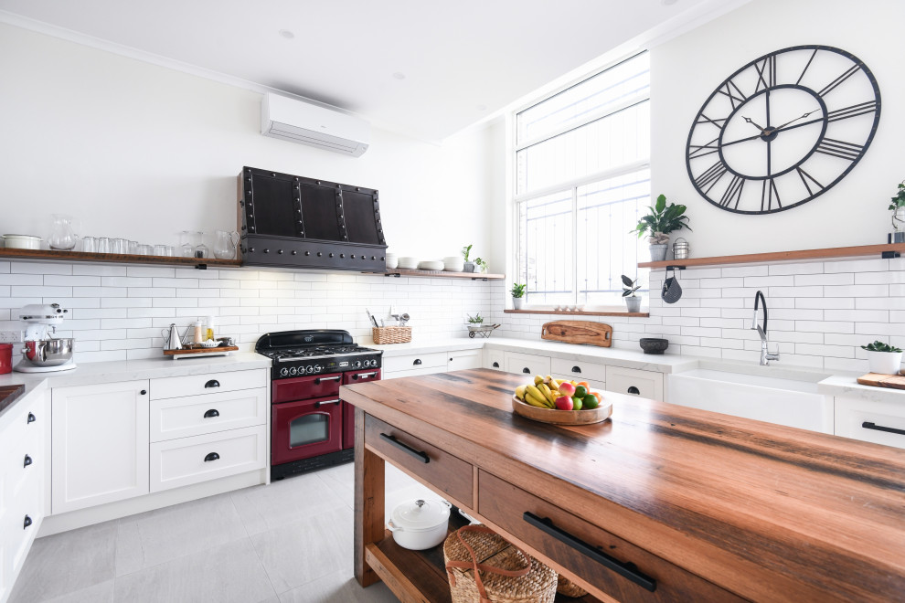 Inspiration for a large country u-shaped open plan kitchen in Sydney with a farmhouse sink, shaker cabinets, white cabinets, quartz benchtops, white splashback, ceramic splashback, coloured appliances, with island, grey floor and grey benchtop.