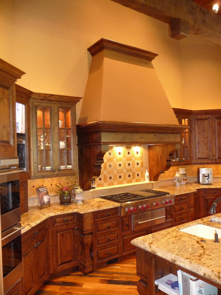 Inspiration for a huge u-shaped medium tone wood floor kitchen remodel in Phoenix with medium tone wood cabinets, granite countertops, multicolored backsplash, stone tile backsplash, stainless steel appliances, an island, an undermount sink and raised-panel cabinets