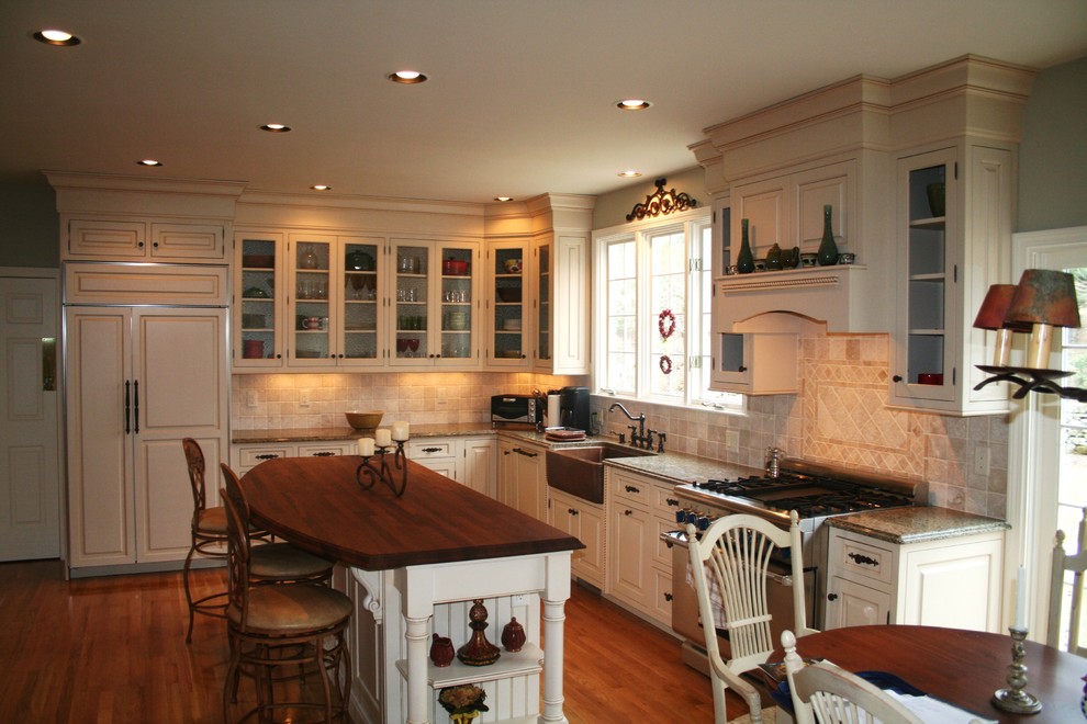 Traditional kitchen in Boston with glass-front cabinets, a farmhouse sink, wood benchtops and panelled appliances.