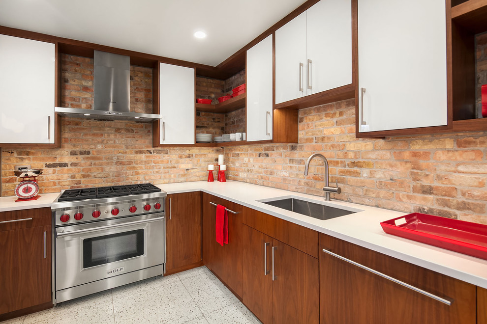 This is an example of a mid-sized midcentury l-shaped eat-in kitchen in Chicago with an undermount sink, flat-panel cabinets, white cabinets, brown splashback, brick splashback, stainless steel appliances, terrazzo floors, with island, beige floor and quartz benchtops.