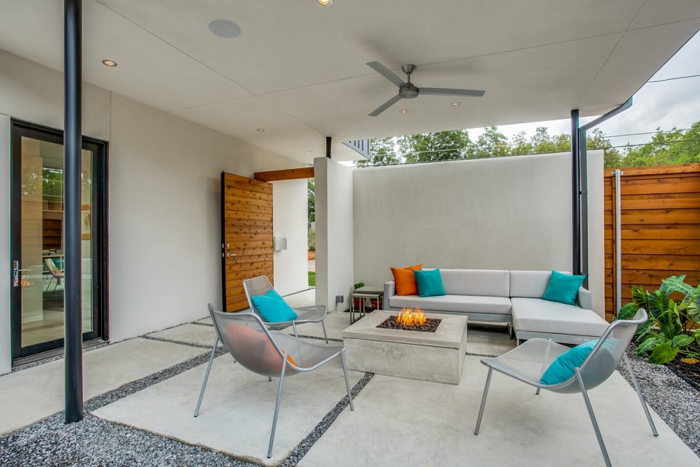 This is an example of a mid-sized contemporary courtyard patio in Dallas with a fire feature, concrete slab and a roof extension.