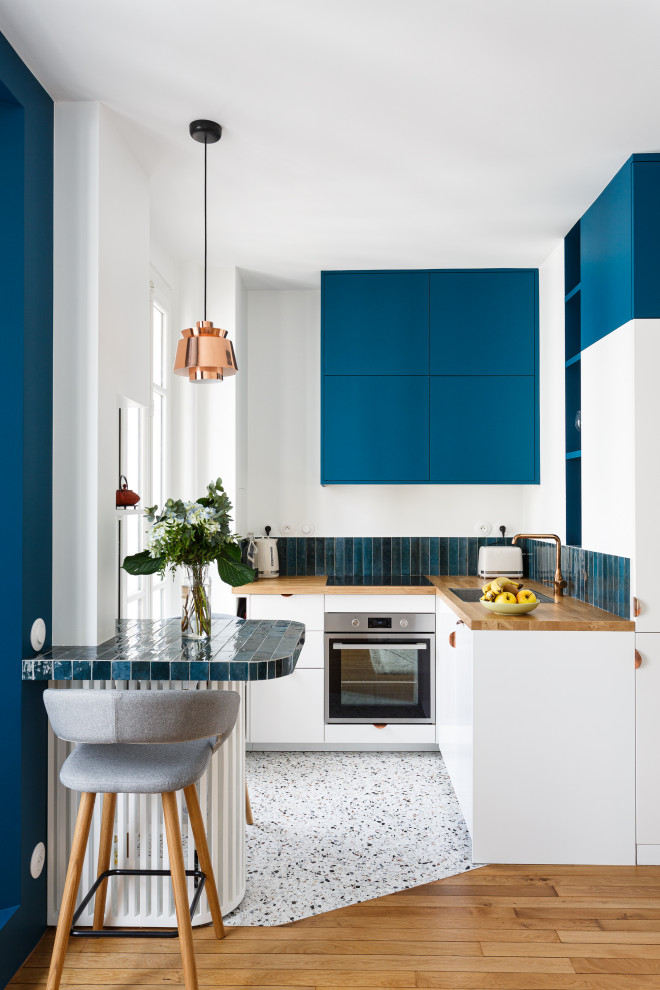 Idéer för att renovera ett litet funkis brun brunt kök, med en enkel diskho, släta luckor, blå skåp, träbänkskiva, blått stänkskydd, stänkskydd i keramik, integrerade vitvaror, terrazzogolv och flerfärgat golv