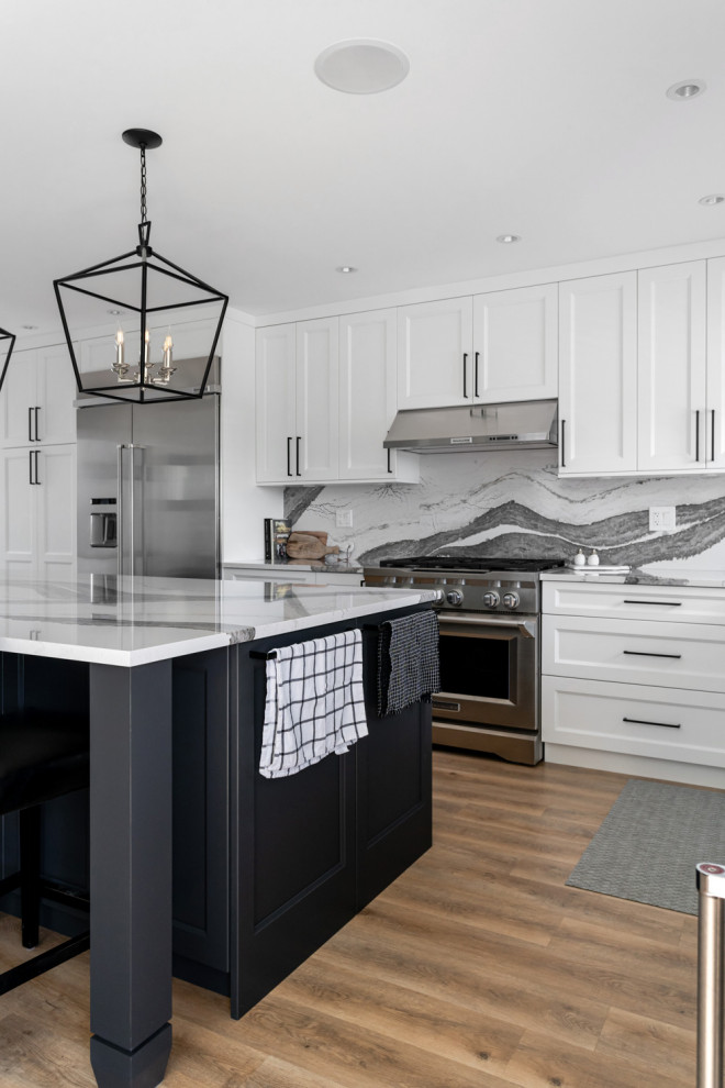 Mid-sized transitional u-shaped medium tone wood floor and brown floor eat-in kitchen photo with an undermount sink, recessed-panel cabinets, white cabinets, quartz countertops, white backsplash, stone slab backsplash, stainless steel appliances, an island and white countertops