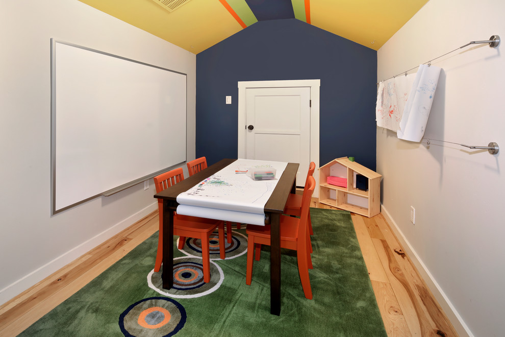 This is an example of a small beach style gender-neutral kids' playroom for kids 4-10 years old in Orange County with blue walls and light hardwood floors.