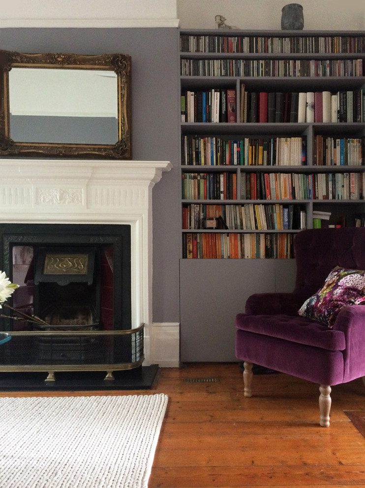 Photo of a small contemporary formal enclosed living room in London with purple walls, medium hardwood floors, a hanging fireplace, a tile fireplace surround, no tv and brown floor.