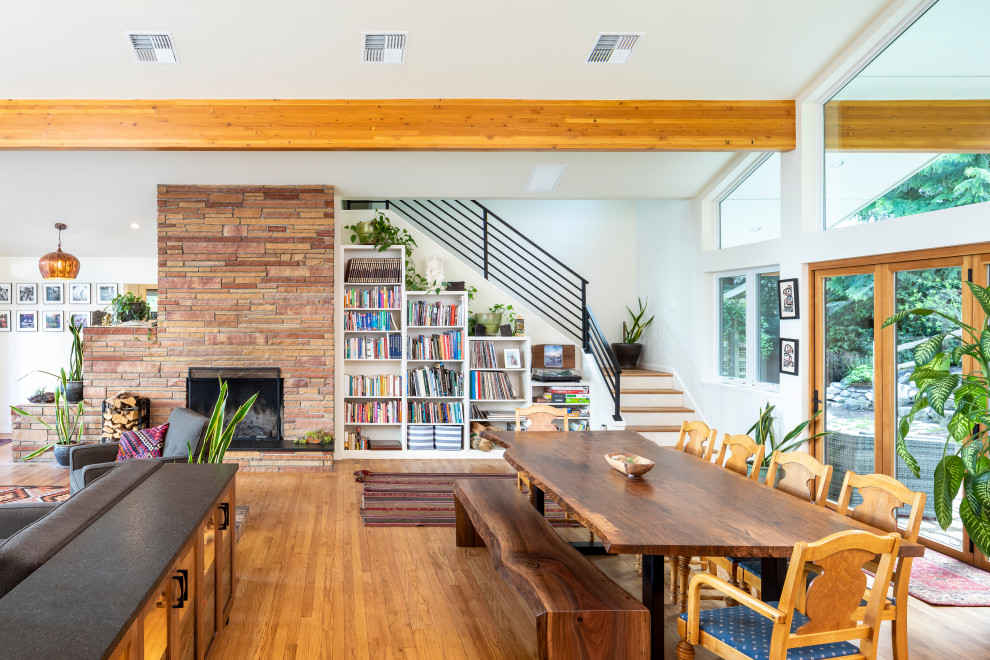 Mid-sized contemporary open plan dining in Seattle with white walls, medium hardwood floors, a standard fireplace and exposed beam.