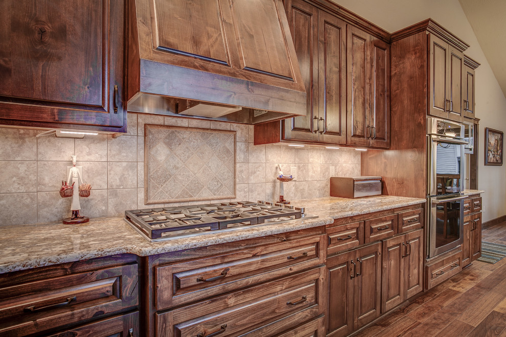 Large mountain style u-shaped medium tone wood floor eat-in kitchen photo in Seattle with an undermount sink, raised-panel cabinets, medium tone wood cabinets, granite countertops, beige backsplash, ceramic backsplash, stainless steel appliances and an island