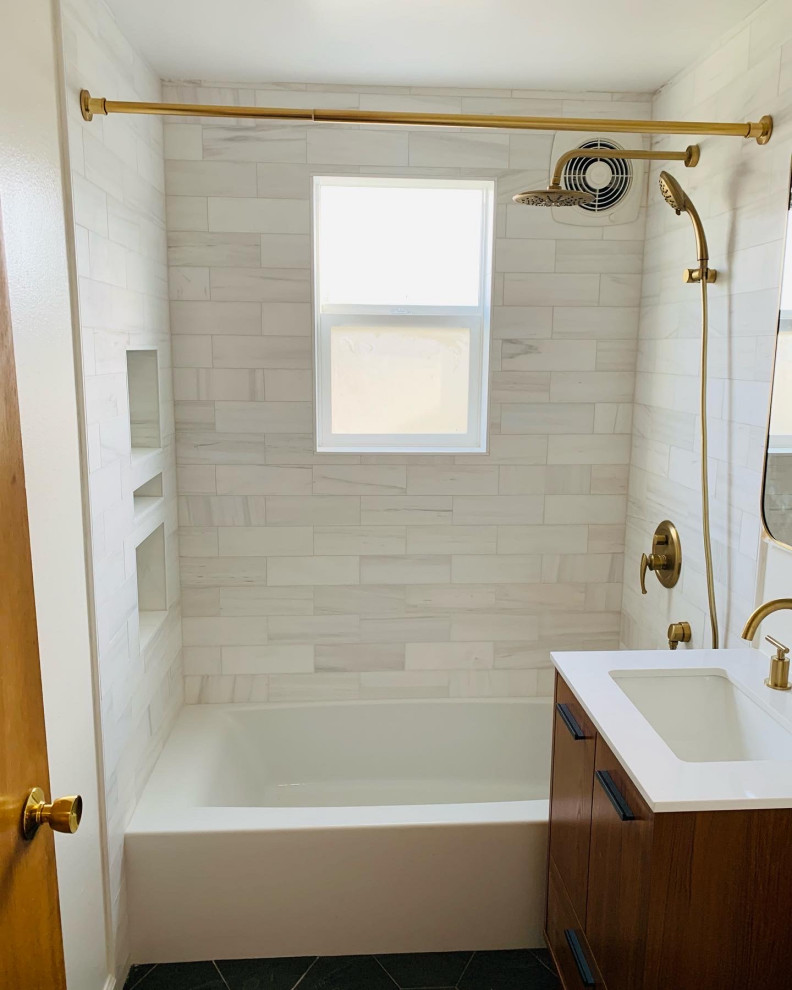Inredning av ett badrum, med bruna skåp, ett fristående badkar, en dusch/badkar-kombination, en toalettstol med hel cisternkåpa, vit kakel, mosaikgolv, grått golv och dusch med duschdraperi