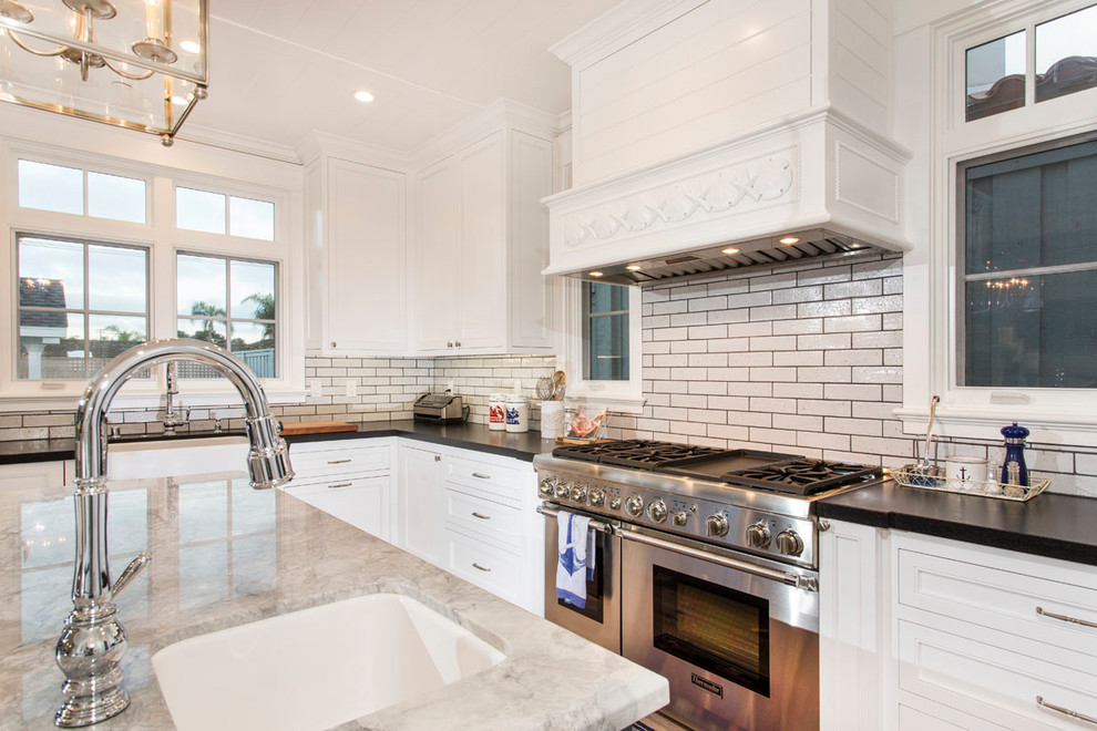 Photo of a mid-sized traditional u-shaped open plan kitchen in San Diego with an undermount sink, shaker cabinets, white cabinets, granite benchtops, beige splashback, porcelain splashback, stainless steel appliances, light hardwood floors, with island and beige floor.