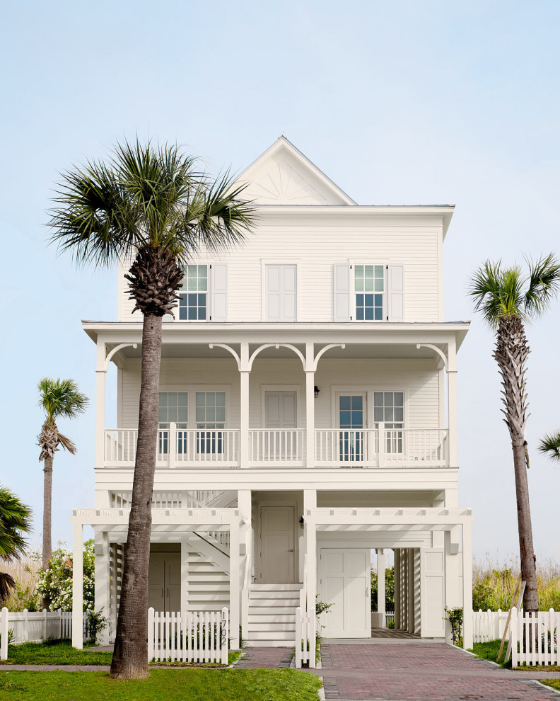 Beach Bungalow - Large beach style white three-story wood house exterior photo in Houston with a shingle roof