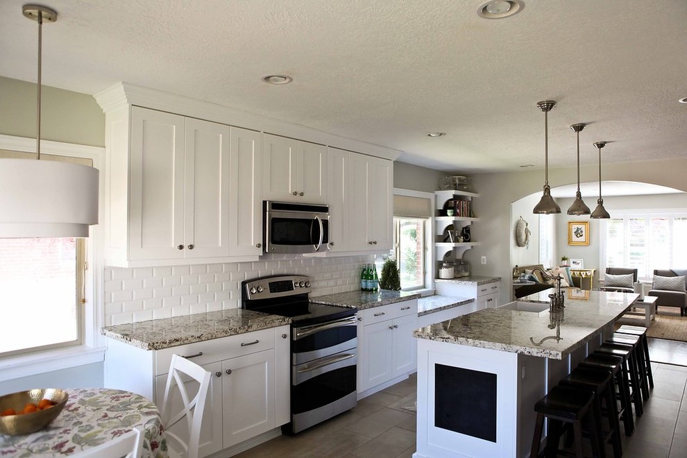 This is an example of a mid-sized eclectic eat-in kitchen in Salt Lake City with a farmhouse sink, shaker cabinets, white cabinets, granite benchtops, white splashback, ceramic splashback, stainless steel appliances, ceramic floors and with island.