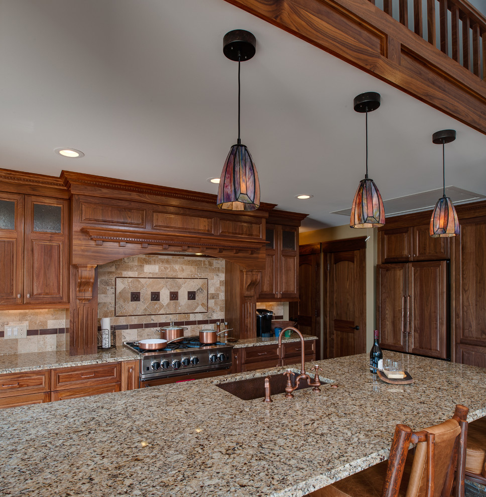 Large mountain style u-shaped medium tone wood floor and brown floor open concept kitchen photo with an undermount sink, raised-panel cabinets, medium tone wood cabinets, granite countertops, beige backsplash, travertine backsplash, paneled appliances and an island