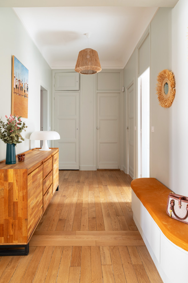 This is an example of a large contemporary foyer in Paris with green walls, light hardwood floors, brown floor and decorative wall panelling.
