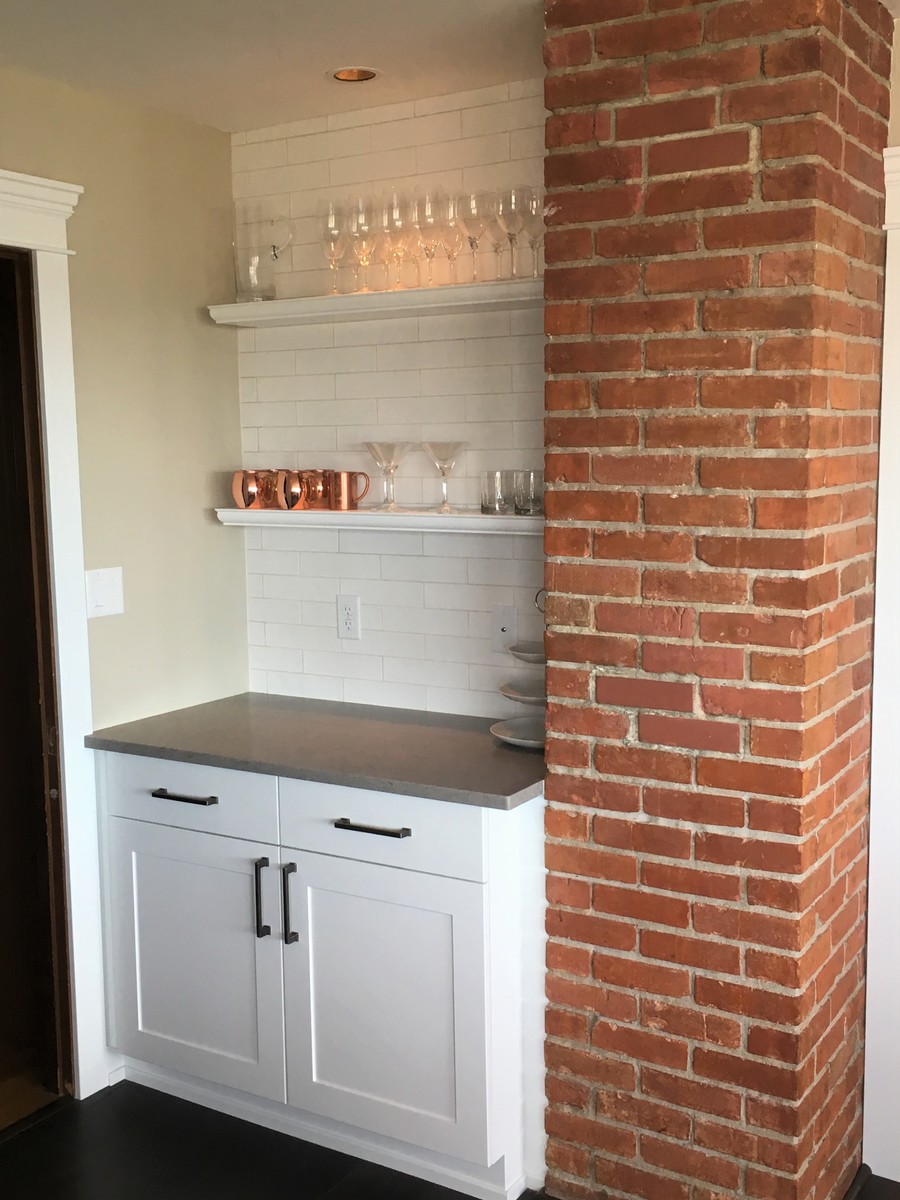 This is an example of a mid-sized arts and crafts u-shaped eat-in kitchen in Seattle with an undermount sink, shaker cabinets, white cabinets, solid surface benchtops, white splashback, subway tile splashback, stainless steel appliances, dark hardwood floors, a peninsula and brown floor.