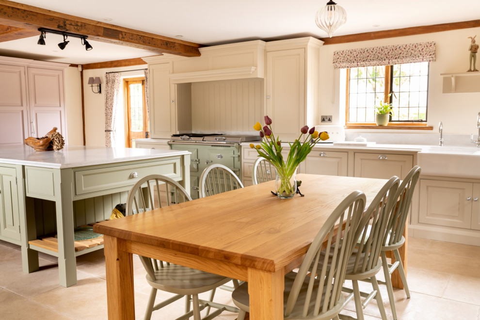 Expansive traditional galley open plan kitchen in Essex with a double-bowl sink, raised-panel cabinets, green cabinets, quartzite benchtops, coloured appliances, porcelain floors, with island, beige floor, white benchtop and exposed beam.