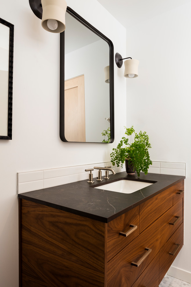Photo of a midcentury 3/4 bathroom in Seattle with medium wood cabinets, a curbless shower, a one-piece toilet, white tile, ceramic tile, white walls, mosaic tile floors, an undermount sink, engineered quartz benchtops, grey floor, an open shower and black benchtops.