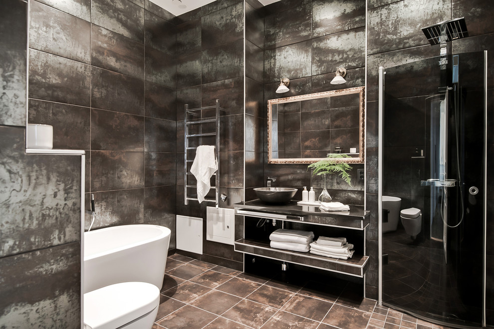 Inspiration for an industrial bathroom in Gothenburg with open cabinets, a wall-mount toilet, brown tile, multi-coloured tile and brown floor.