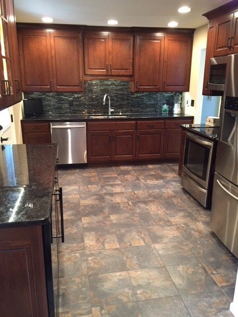 Enclosed kitchen - transitional u-shaped porcelain tile enclosed kitchen idea with an undermount sink, medium tone wood cabinets, granite countertops, black backsplash, mosaic tile backsplash, stainless steel appliances and no island