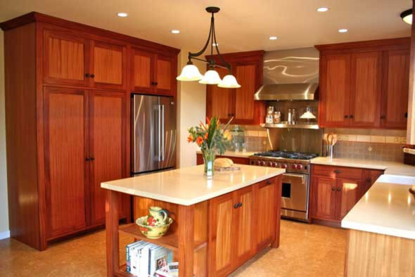 This is an example of a mid-sized arts and crafts u-shaped kitchen pantry in Santa Barbara with a farmhouse sink, recessed-panel cabinets, medium wood cabinets, solid surface benchtops, multi-coloured splashback, ceramic splashback, stainless steel appliances, cork floors and with island.