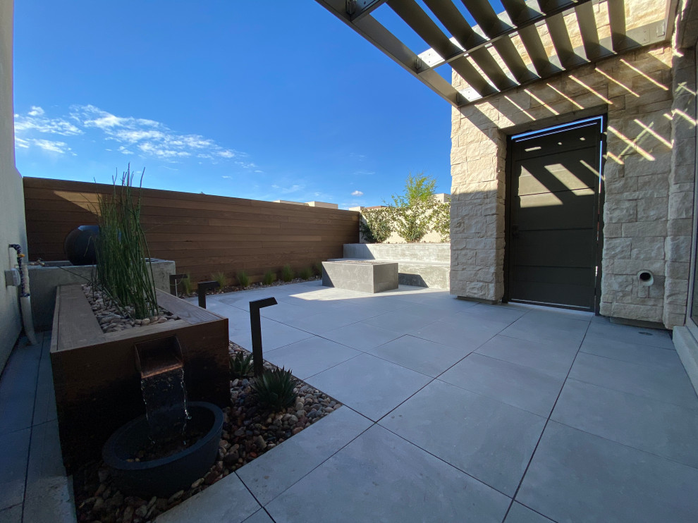 This is an example of a small modern courtyard patio in Las Vegas with a water feature and tile.