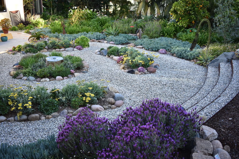 Design ideas for a mid-sized beach style backyard full sun xeriscape for winter in San Diego with a water feature and natural stone pavers.