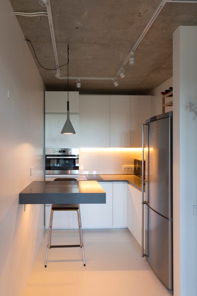 This is an example of a small contemporary l-shaped open plan kitchen in Moscow with flat-panel cabinets, white cabinets, white splashback and stainless steel appliances.
