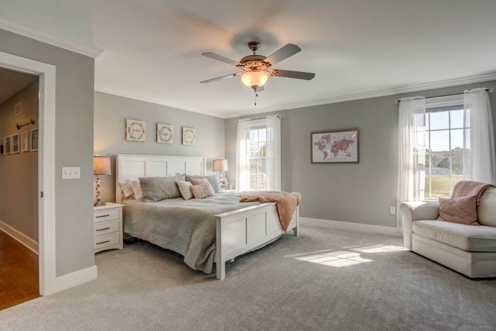Photo of a large rural master bedroom with grey walls, carpet and grey floors.