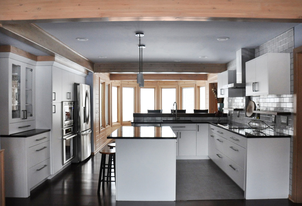 Eat-in kitchen - mid-sized transitional l-shaped dark wood floor eat-in kitchen idea in Grand Rapids with an undermount sink, flat-panel cabinets, white cabinets, soapstone countertops, white backsplash, subway tile backsplash, stainless steel appliances and an island